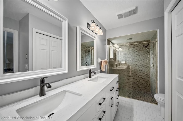 bathroom featuring vanity, a shower with shower door, tile patterned floors, and toilet