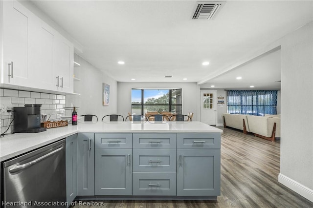 kitchen featuring tasteful backsplash, kitchen peninsula, dishwasher, and white cabinets