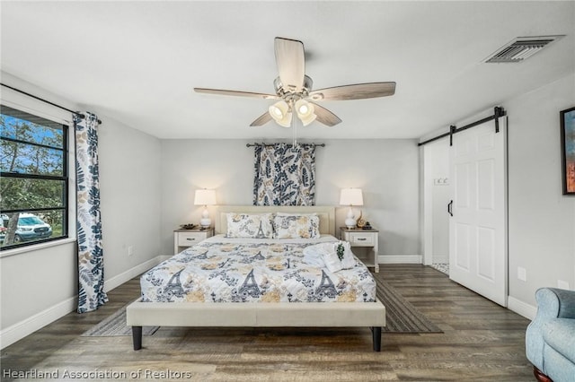 bedroom featuring a barn door, dark hardwood / wood-style floors, and ceiling fan