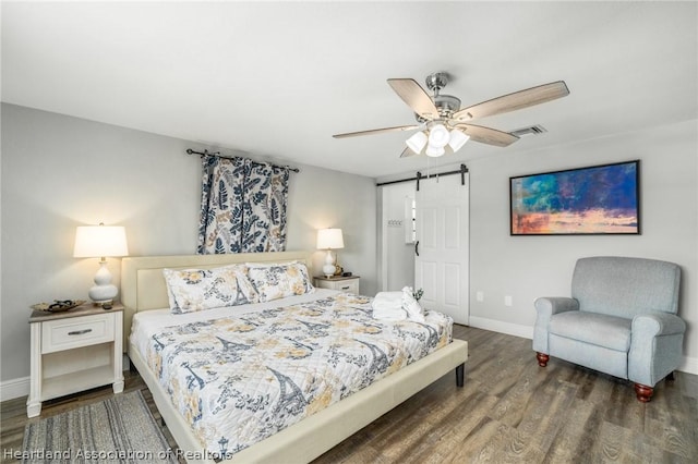 bedroom with a barn door, ceiling fan, and dark wood-type flooring