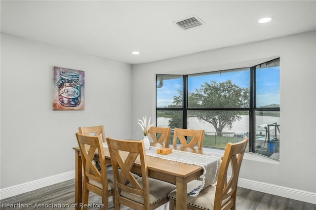 dining space with a water view and dark hardwood / wood-style floors