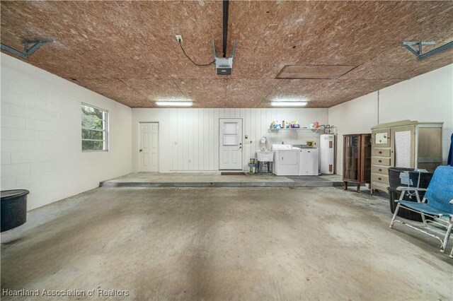 garage with washer and clothes dryer, electric water heater, and sink