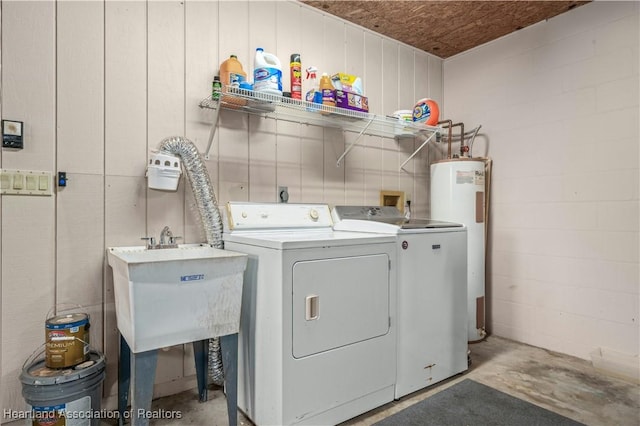 washroom featuring electric water heater, washer and clothes dryer, and sink