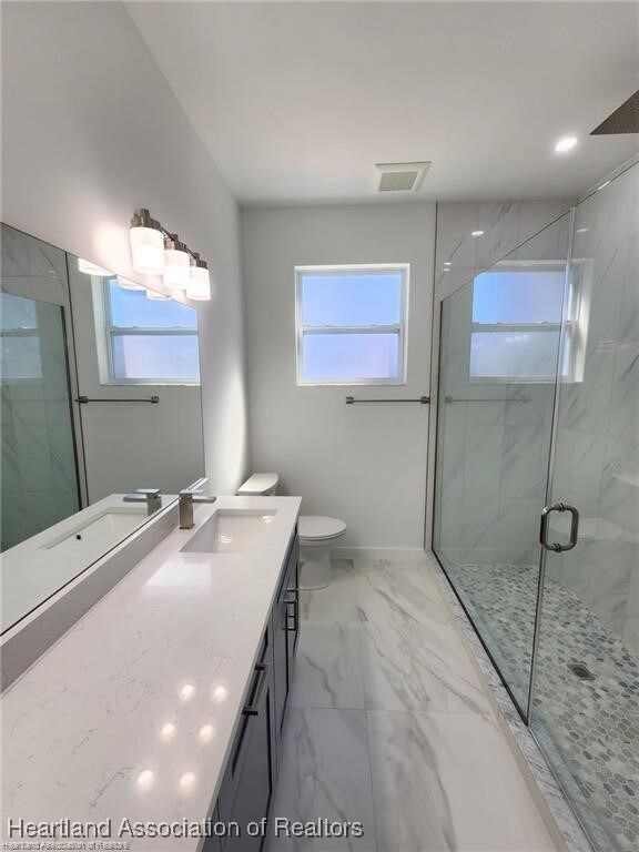 4983 San Lorenzo Dr, Sebring, FL 33872 - bathroom featuring toilet, vanity, a marble finish shower, marble finish floor, and visible vents
