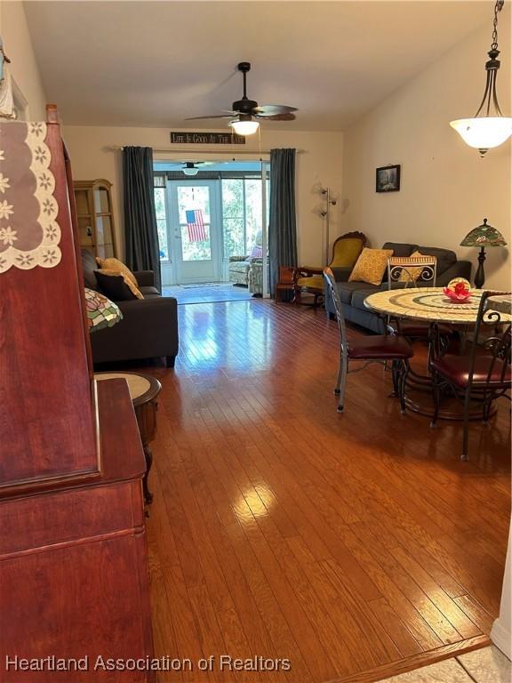 living room featuring ceiling fan, wood-type flooring, visible vents, and vaulted ceiling