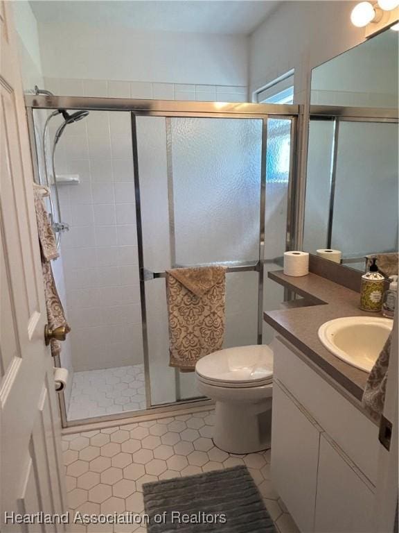 full bath featuring a stall shower, vanity, toilet, and tile patterned floors