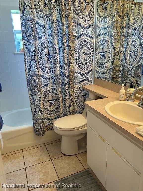 bathroom featuring tile patterned flooring, shower / bathtub combination with curtain, vanity, and toilet