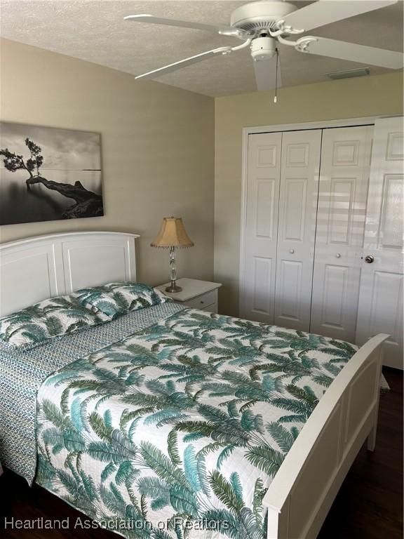 bedroom featuring ceiling fan, a textured ceiling, dark wood-style flooring, and a closet