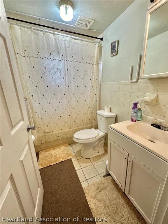 bathroom featuring a shower with curtain, vanity, tile walls, tile patterned flooring, and toilet