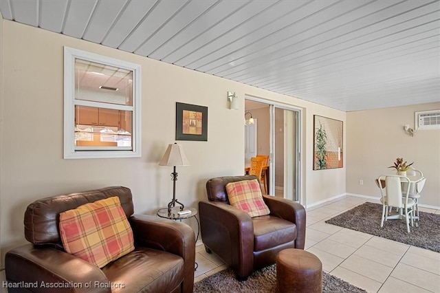 sitting room featuring light tile patterned flooring, baseboards, and a wall mounted AC