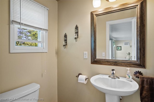 half bathroom featuring toilet, visible vents, and a sink