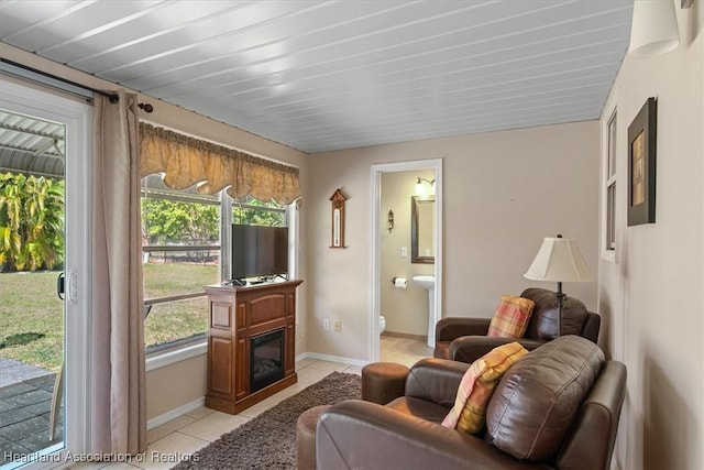 interior space featuring a glass covered fireplace, baseboards, and light tile patterned flooring