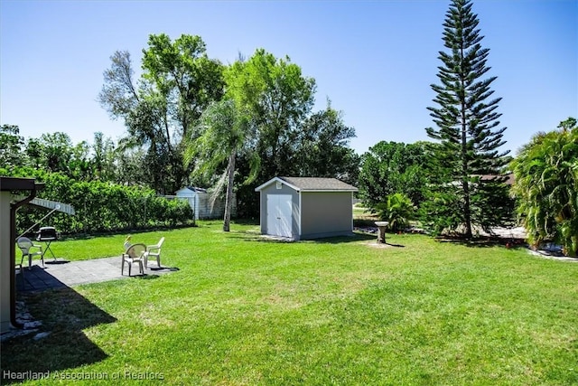 view of yard with an outdoor structure, a storage shed, a patio, and fence