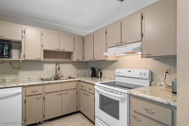 kitchen with under cabinet range hood, light countertops, white appliances, a textured ceiling, and a sink