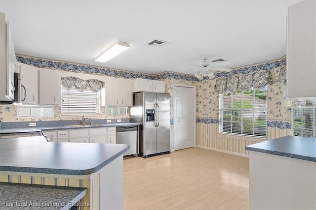 kitchen featuring kitchen peninsula, stainless steel appliances, ceiling fan, sink, and white cabinets