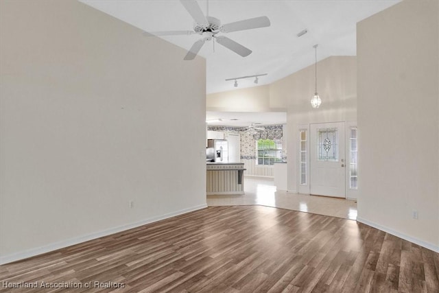 unfurnished living room featuring ceiling fan, hardwood / wood-style floors, track lighting, and lofted ceiling