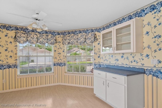 interior space with ceiling fan, light hardwood / wood-style flooring, and white cabinets