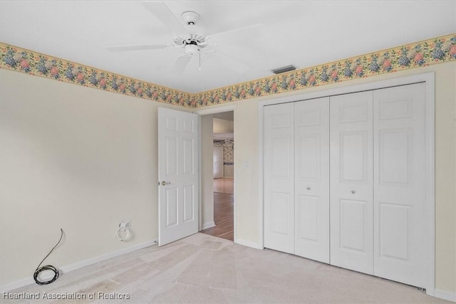 unfurnished bedroom with ceiling fan, light carpet, and a closet