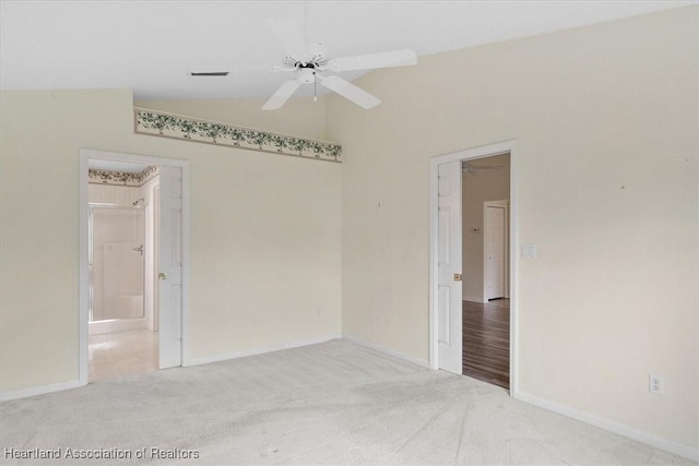 carpeted spare room featuring ceiling fan and vaulted ceiling