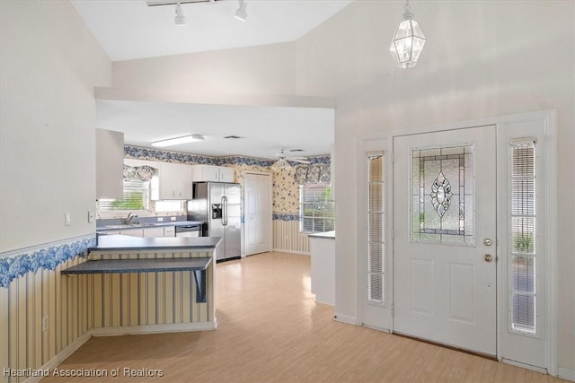 foyer with light wood-type flooring, sink, and vaulted ceiling