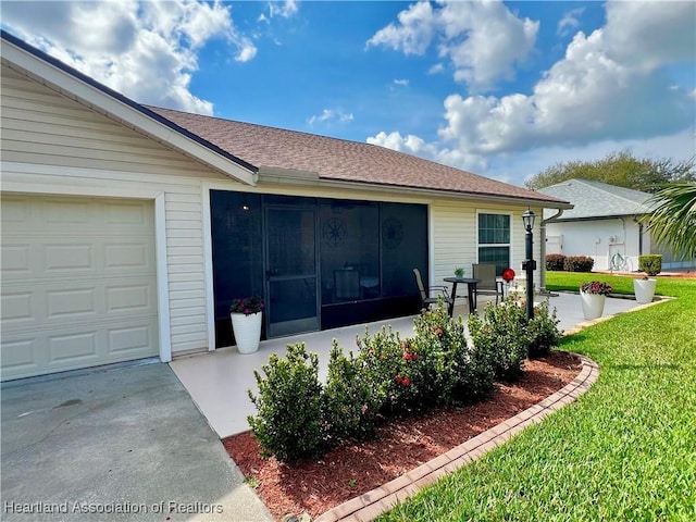 view of side of home featuring a garage, a lawn, and roof with shingles