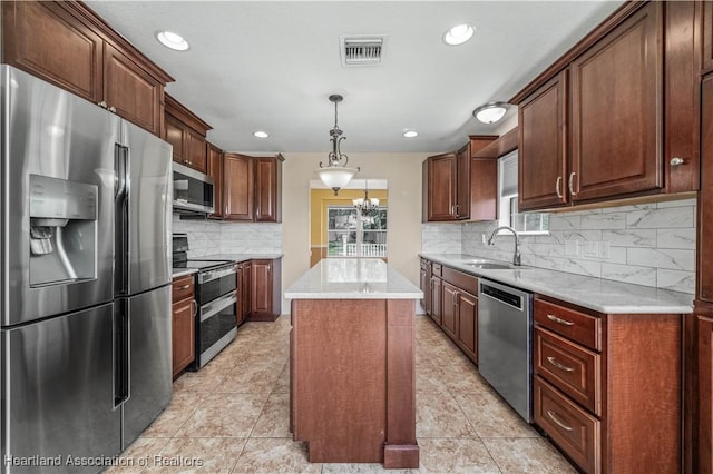 kitchen with sink, decorative backsplash, decorative light fixtures, a kitchen island, and stainless steel appliances