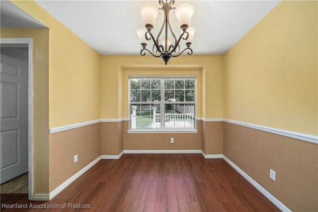 unfurnished dining area with dark hardwood / wood-style floors and an inviting chandelier