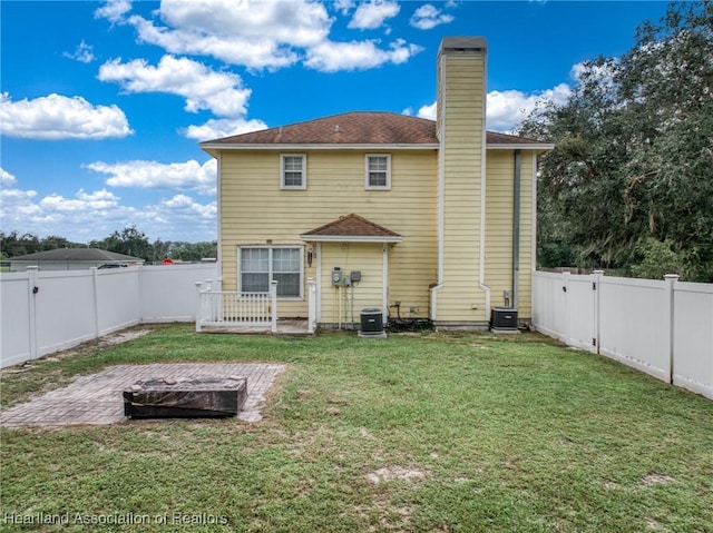 rear view of house with cooling unit and a yard