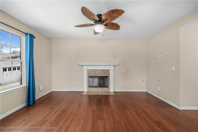 unfurnished living room with ceiling fan, a high end fireplace, and dark wood-type flooring