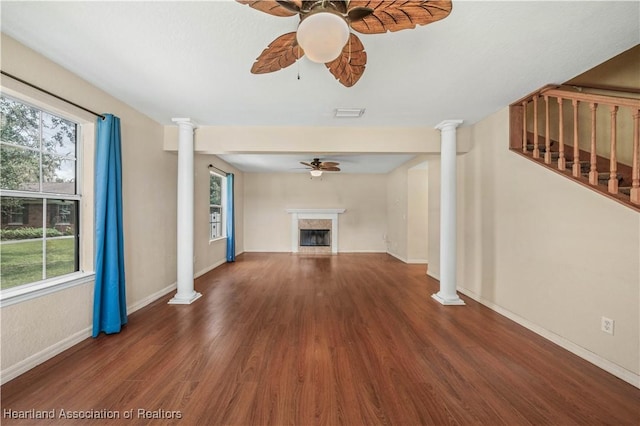 unfurnished living room with ceiling fan, dark hardwood / wood-style flooring, and decorative columns