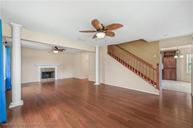 unfurnished living room with a fireplace, ceiling fan with notable chandelier, and dark hardwood / wood-style floors