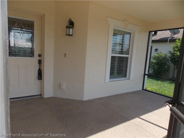 view of exterior entry with a patio area