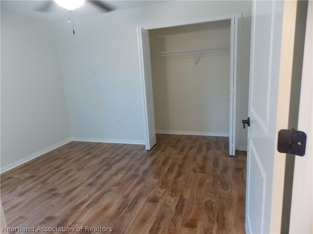 unfurnished bedroom with a closet, dark hardwood / wood-style floors, and ceiling fan