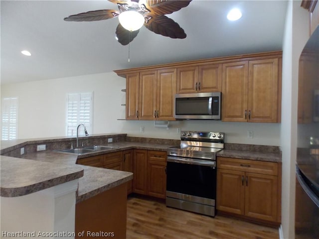 kitchen with ceiling fan, sink, kitchen peninsula, wood-type flooring, and appliances with stainless steel finishes