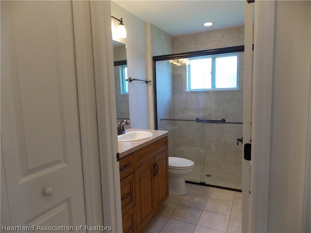 bathroom with tile patterned floors, vanity, an enclosed shower, and toilet