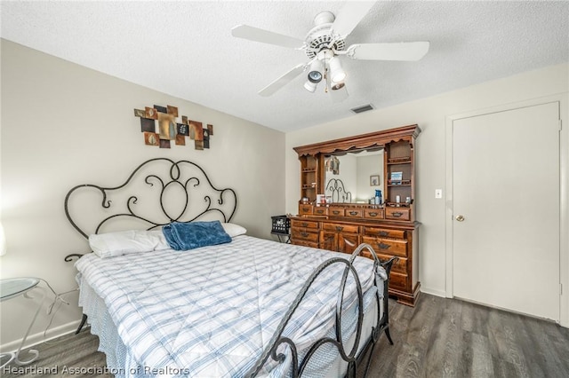 bedroom with a textured ceiling, ceiling fan, and dark wood-type flooring