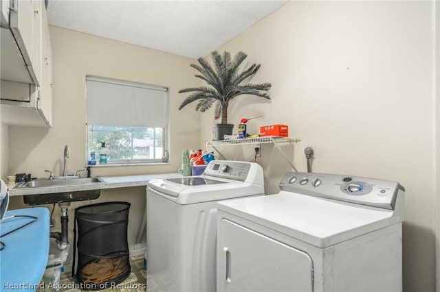 clothes washing area with sink, cabinets, and independent washer and dryer