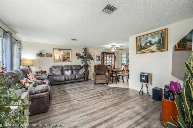 living room featuring hardwood / wood-style floors, a textured ceiling, and ceiling fan