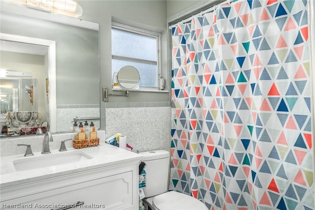 bathroom with a shower with curtain, vanity, toilet, and tile walls