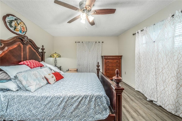 bedroom featuring ceiling fan, hardwood / wood-style floors, and a textured ceiling