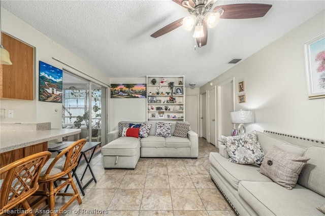 tiled living room with a textured ceiling and ceiling fan