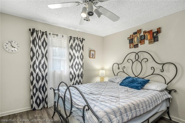 bedroom with a textured ceiling, ceiling fan, and dark wood-type flooring