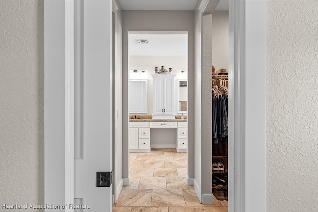 5931 Fig Rd, Sebring, FL 33875 - hall featuring stone tile flooring, a textured wall, visible vents, and a sink