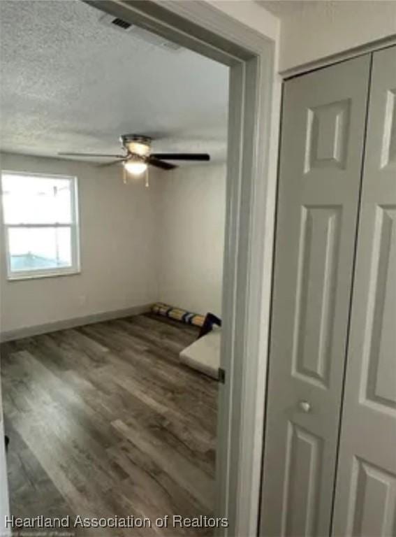 interior space featuring ceiling fan, dark wood-type flooring, and a textured ceiling