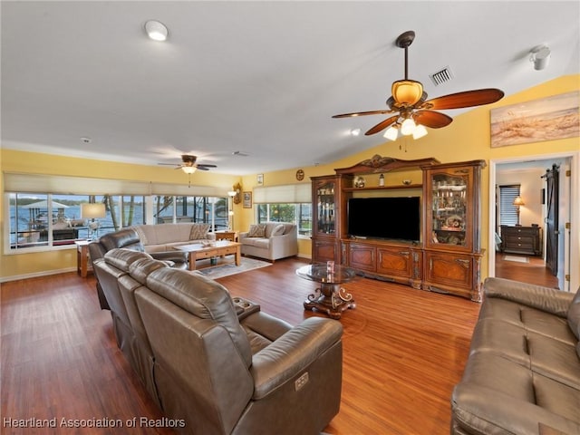 living room with wood-type flooring, vaulted ceiling, and ceiling fan