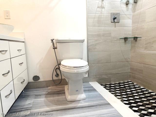 bathroom featuring vanity, toilet, and tiled shower