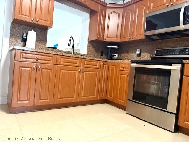 kitchen featuring sink, backsplash, stainless steel appliances, and stone countertops