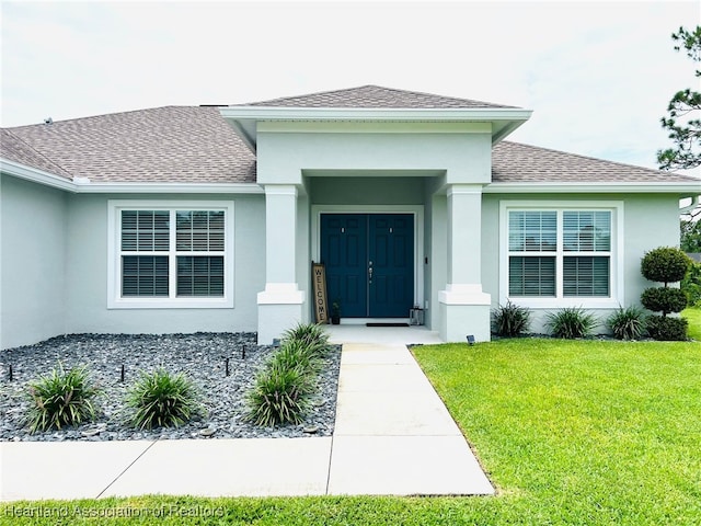 5310 Pebble Dr, Sebring, FL 33872 - view of exterior entry with a shingled roof, a lawn, and stucco siding