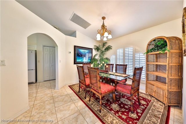 dining space with vaulted ceiling, a chandelier, light tile patterned floors, visible vents, and arched walkways