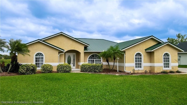 ranch-style home with a front yard, a standing seam roof, metal roof, and stucco siding